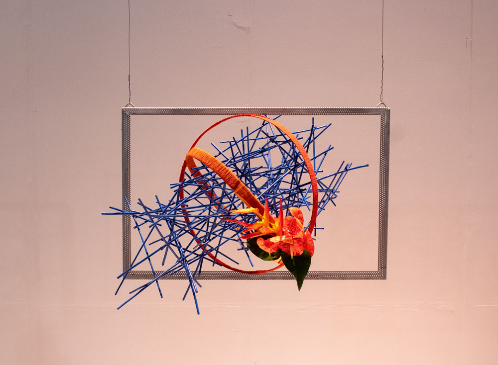 An abstract sculpture with blue rods and orange flowers.