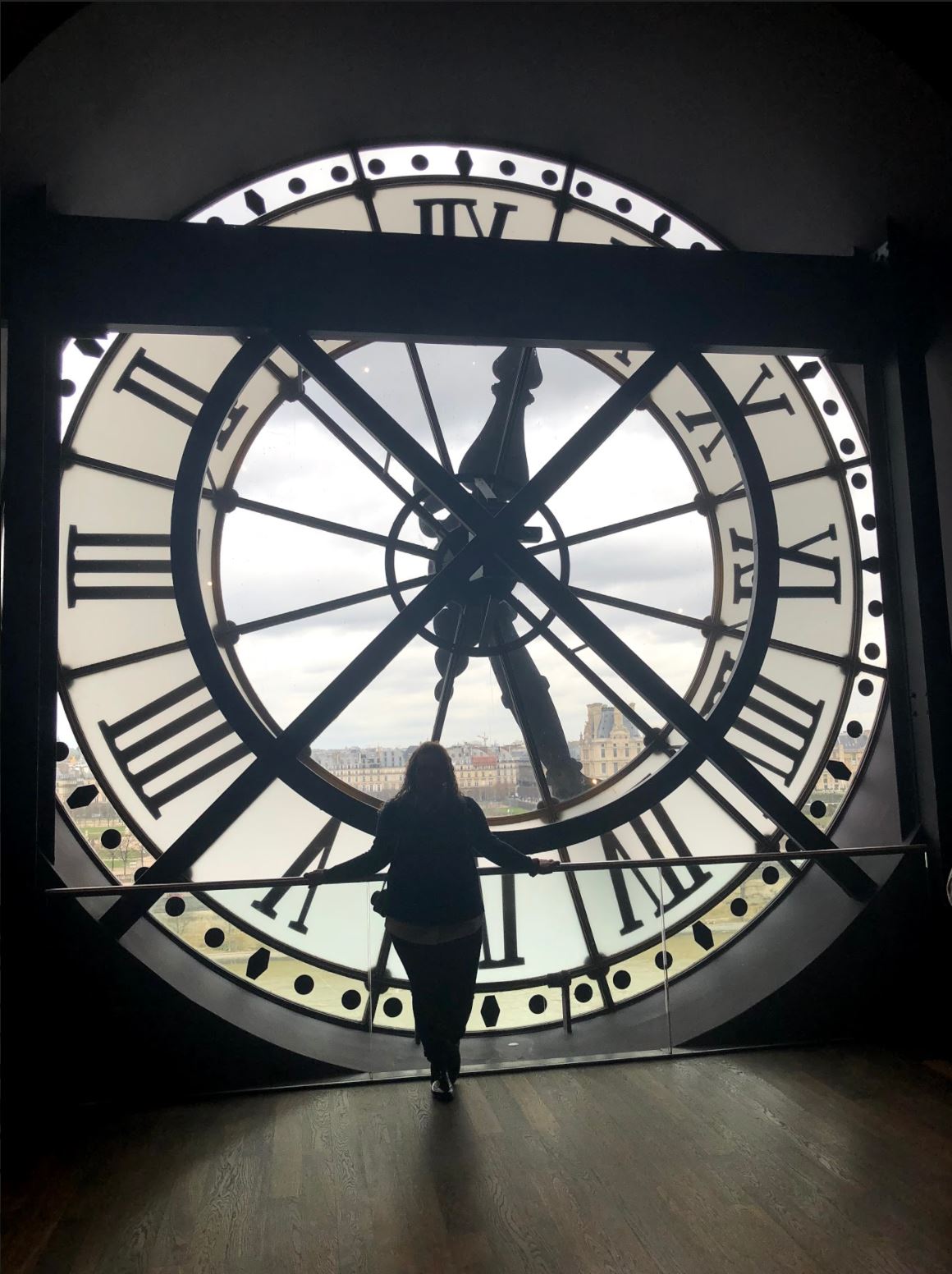 Madison Cline looking outside of clock window in Paris, France