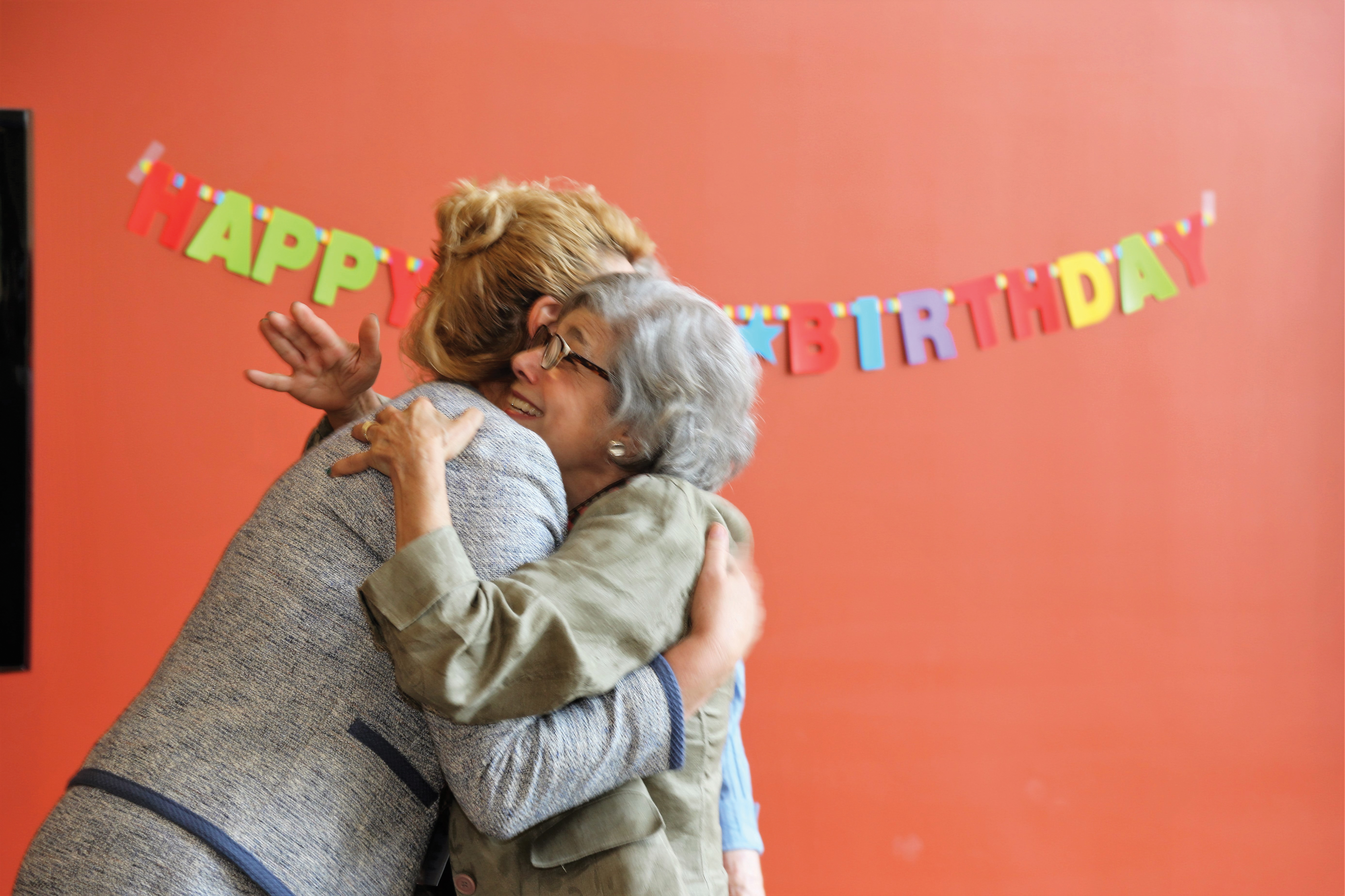 Two Senior women hugging each other at a birthday party.