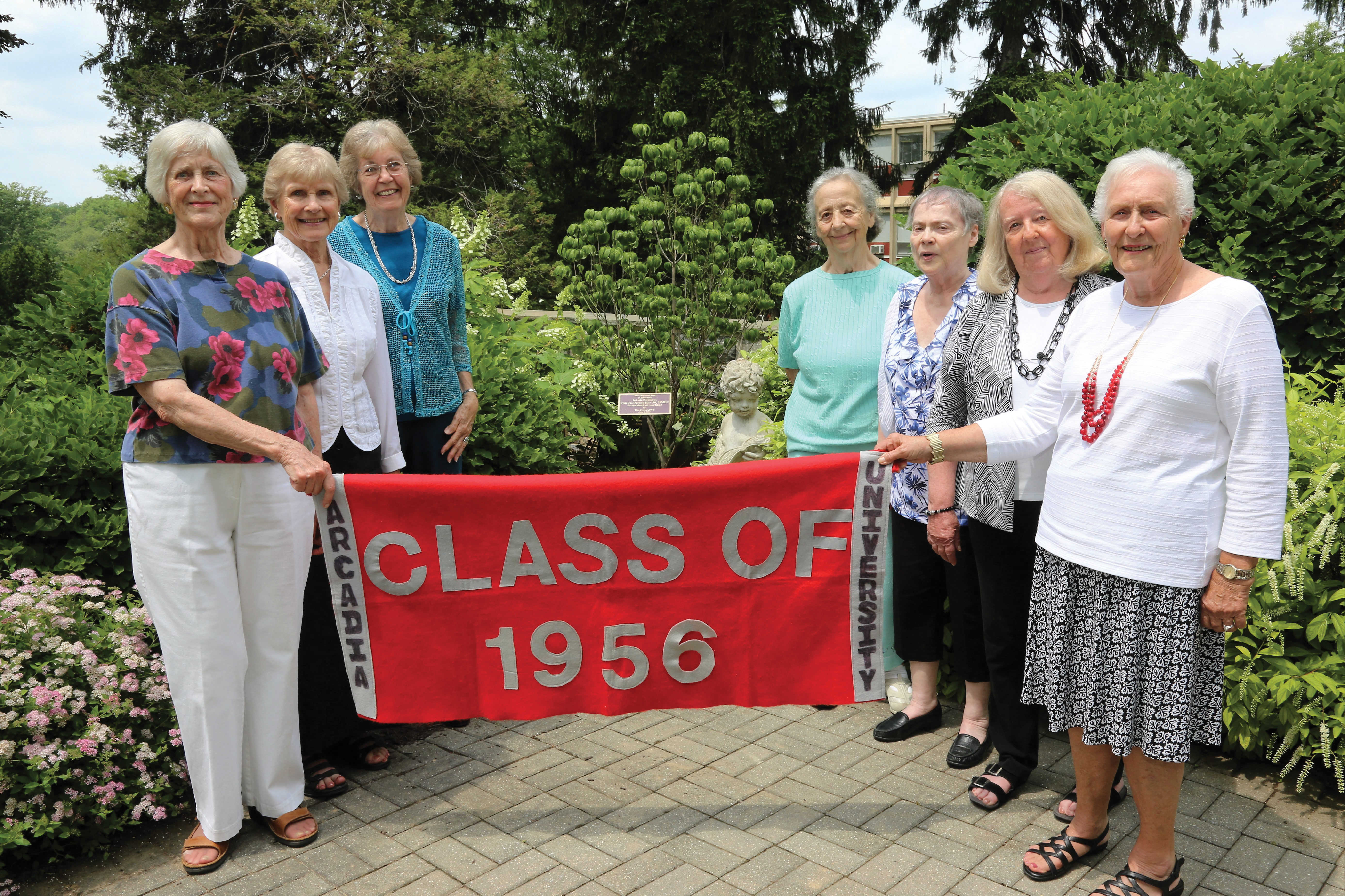 Seven Senior Alumni women group photo holding a banner from the Class of 1956.