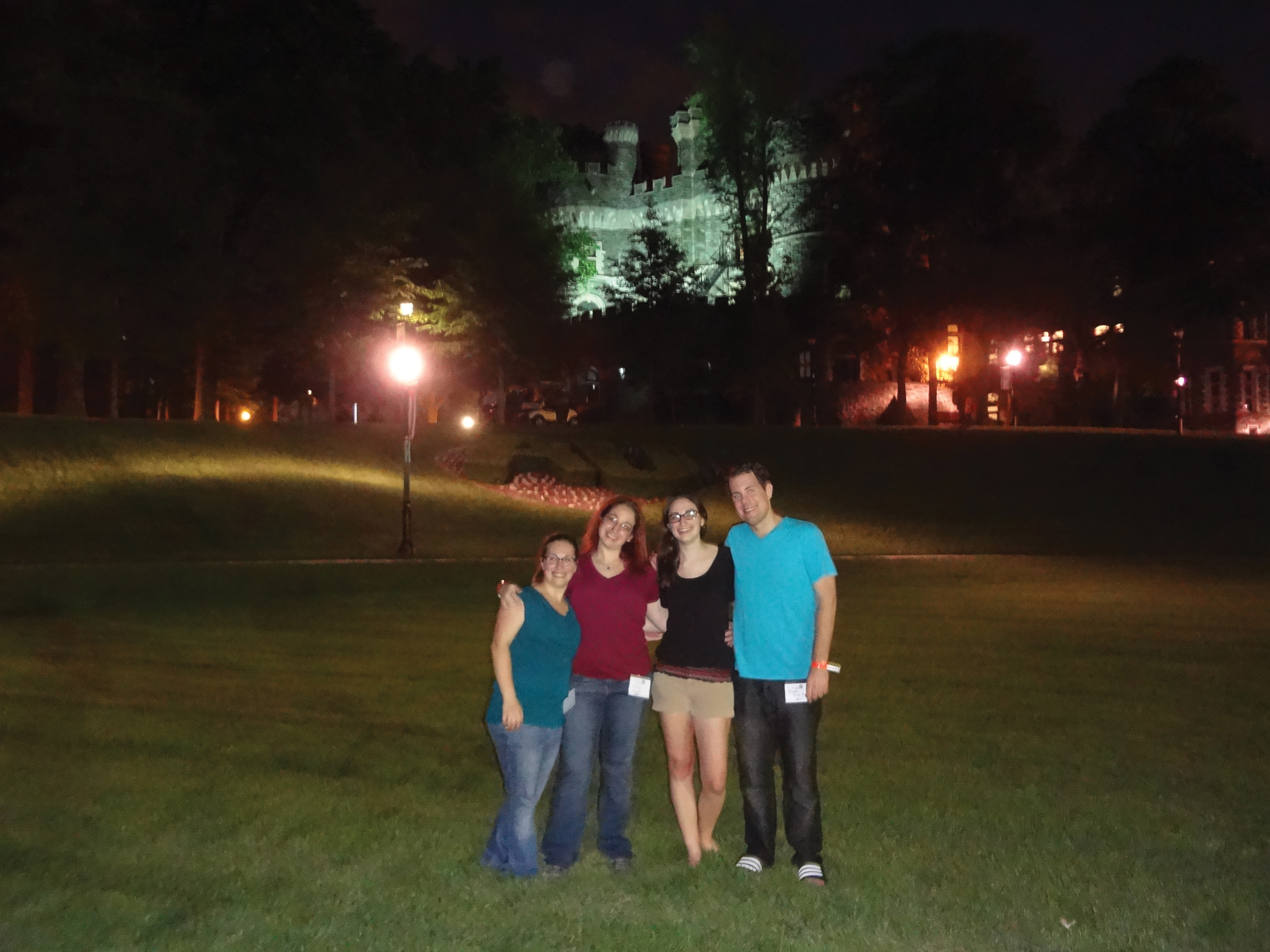 Four Alumni students from the Class of 2011 on Haber Green at night.