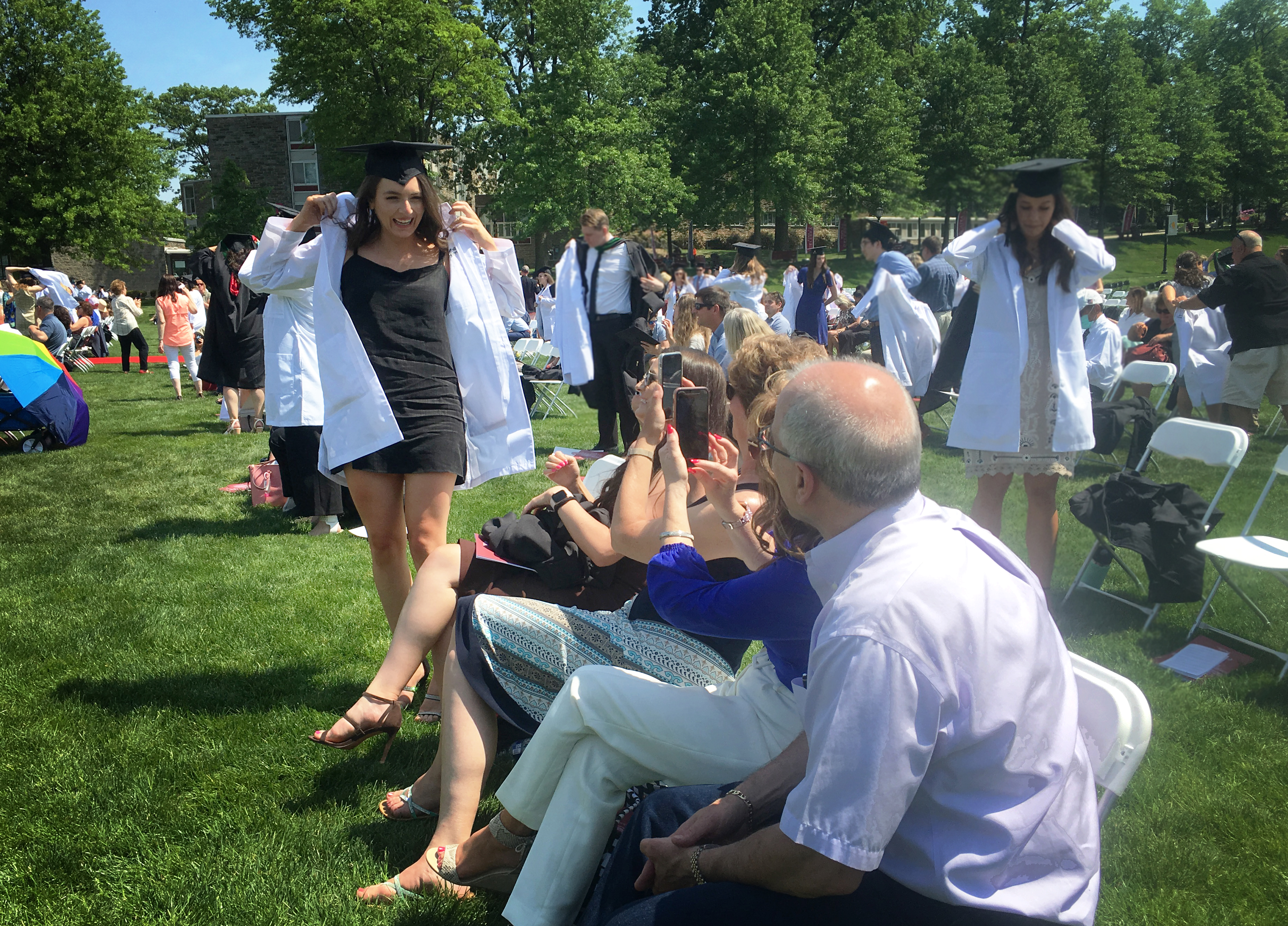 Students receiving their white coats and posing for their families.