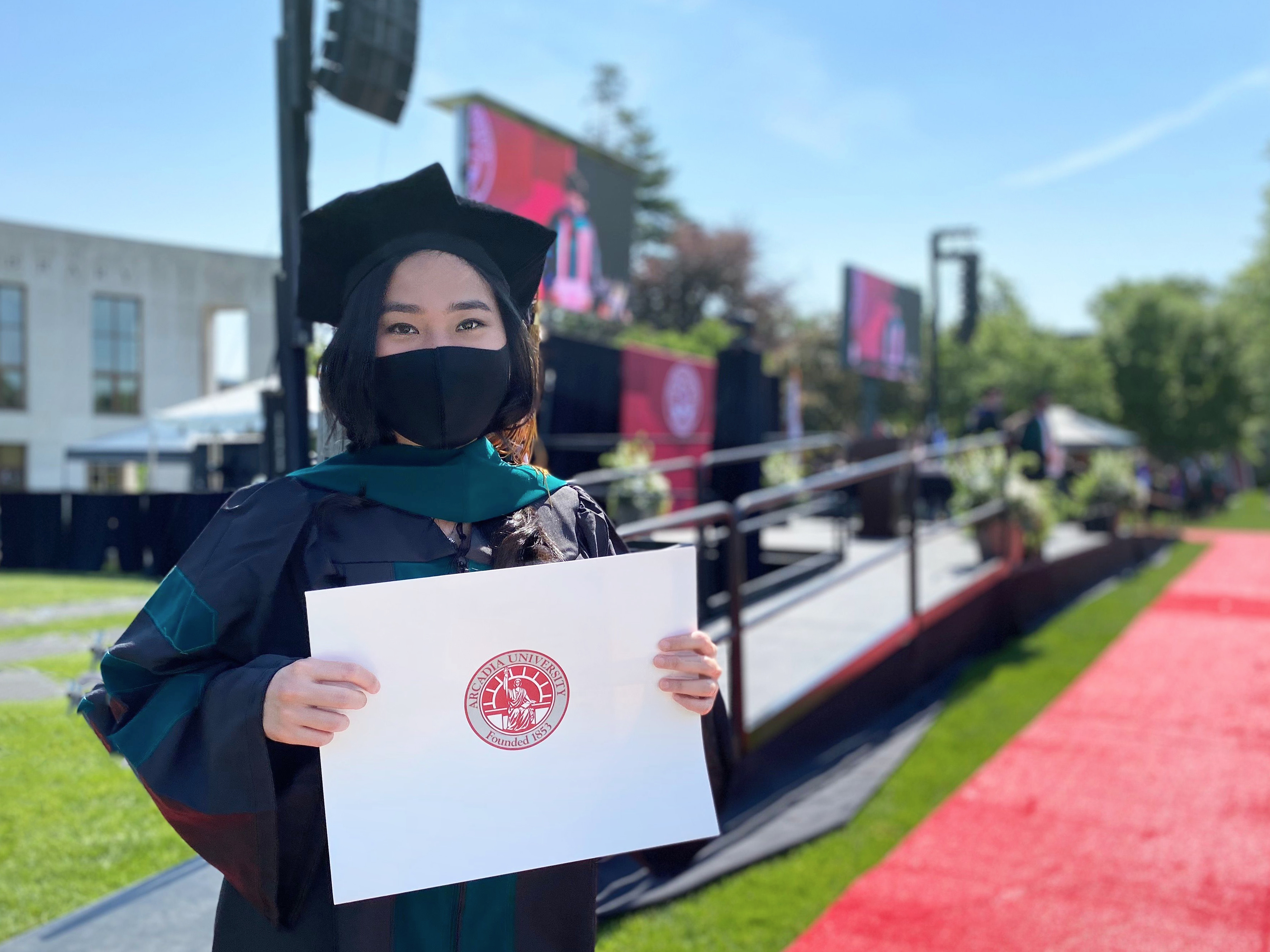 A graduating Doctorate student holding her diploma envelope in her hands.