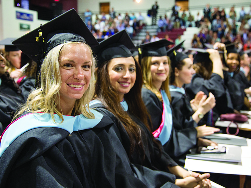 Three graduate women smiling into the camera.