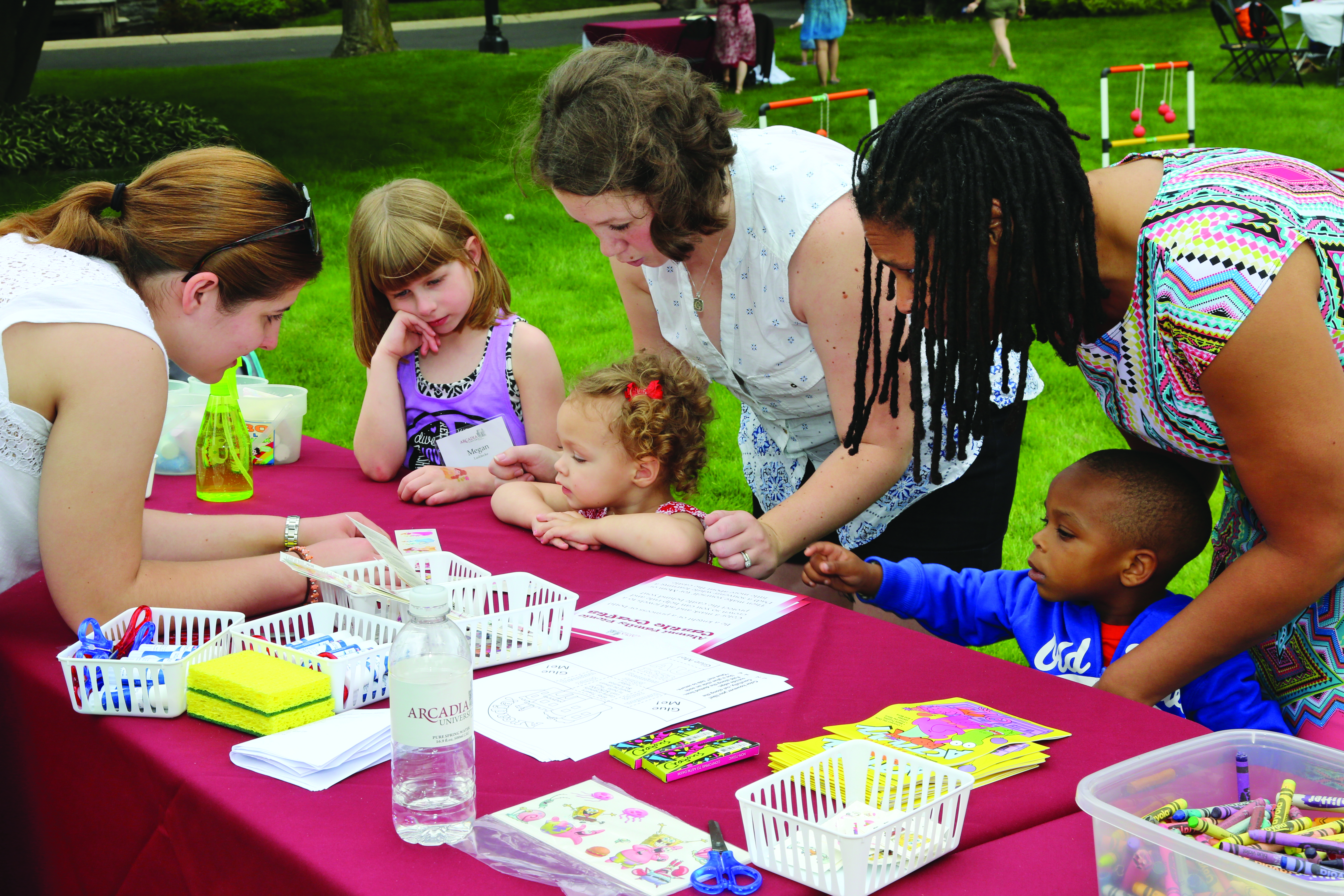 Alumni students with their young children at a craft table.