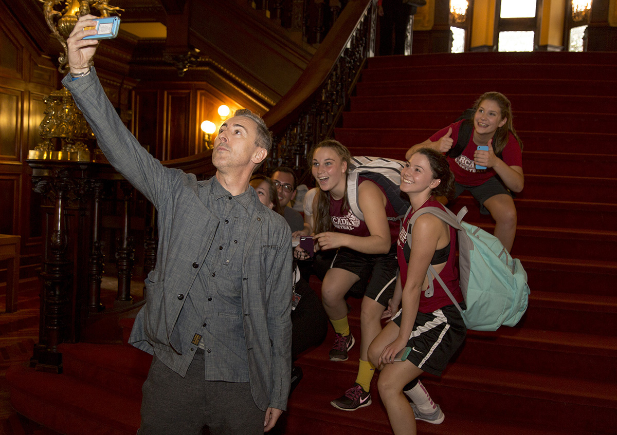 Alan Cumming taking a selfie with several students inside of Grey Towers.