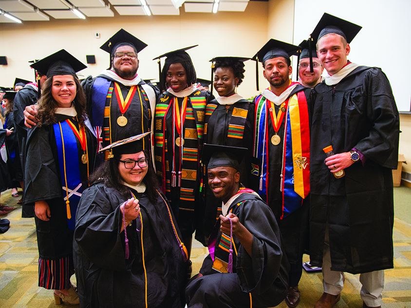 A group of diverse graduate students in regalia.