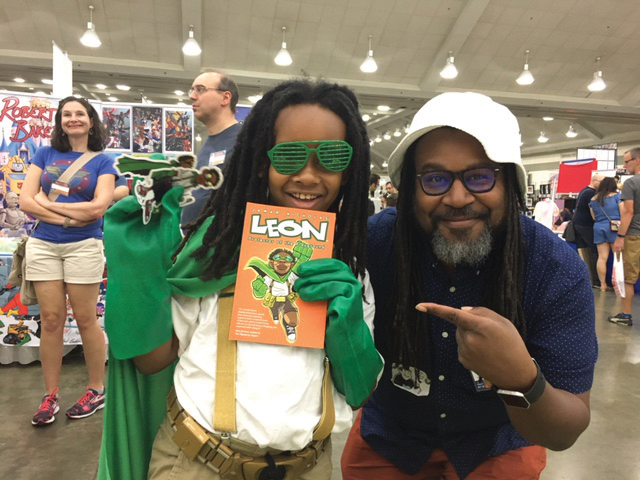Jamar Nicholas posing with a kid wearing a cosplay of his graphic novel character, Leon: Protector of the Playground.