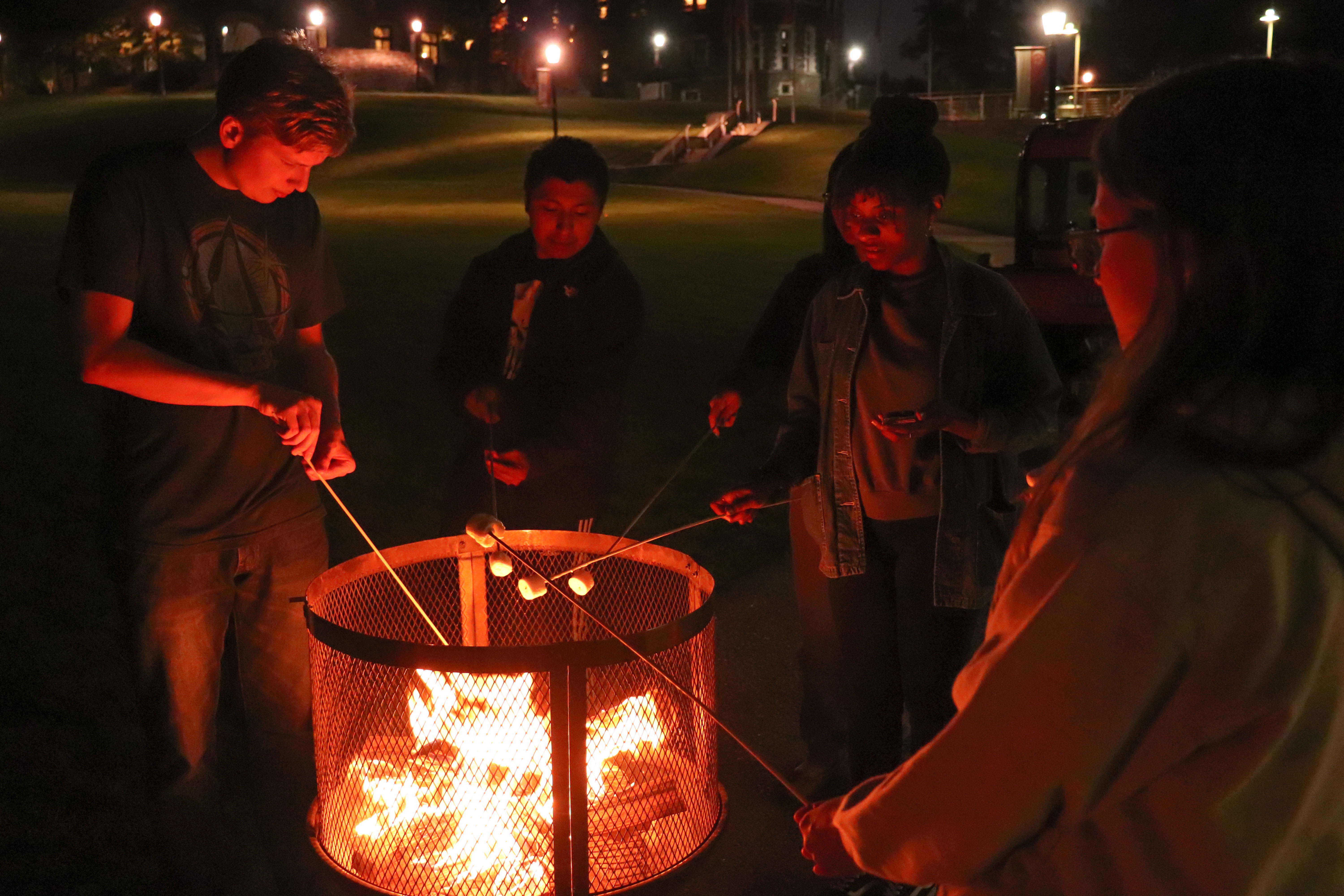 Students at a bonfire toasting their marshmallows.