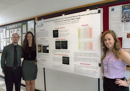 Students standing next to research poster.