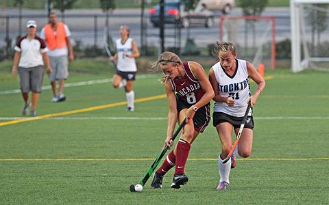 Arcadia Field Hockey player controls the ball with a defender behind her