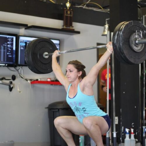 A young woman weightlifting, the weight over her head