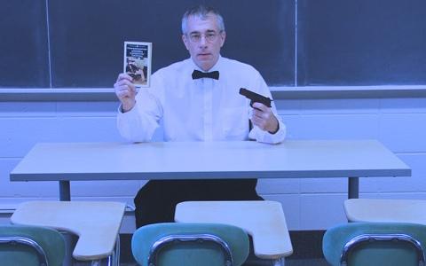 A man wearing a bowtie holding a gun and a book