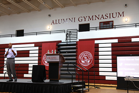 A person giving a speech in the gym.