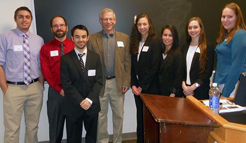 A group of arcadia students and instructors dressed professionally stand in front of a blackboard