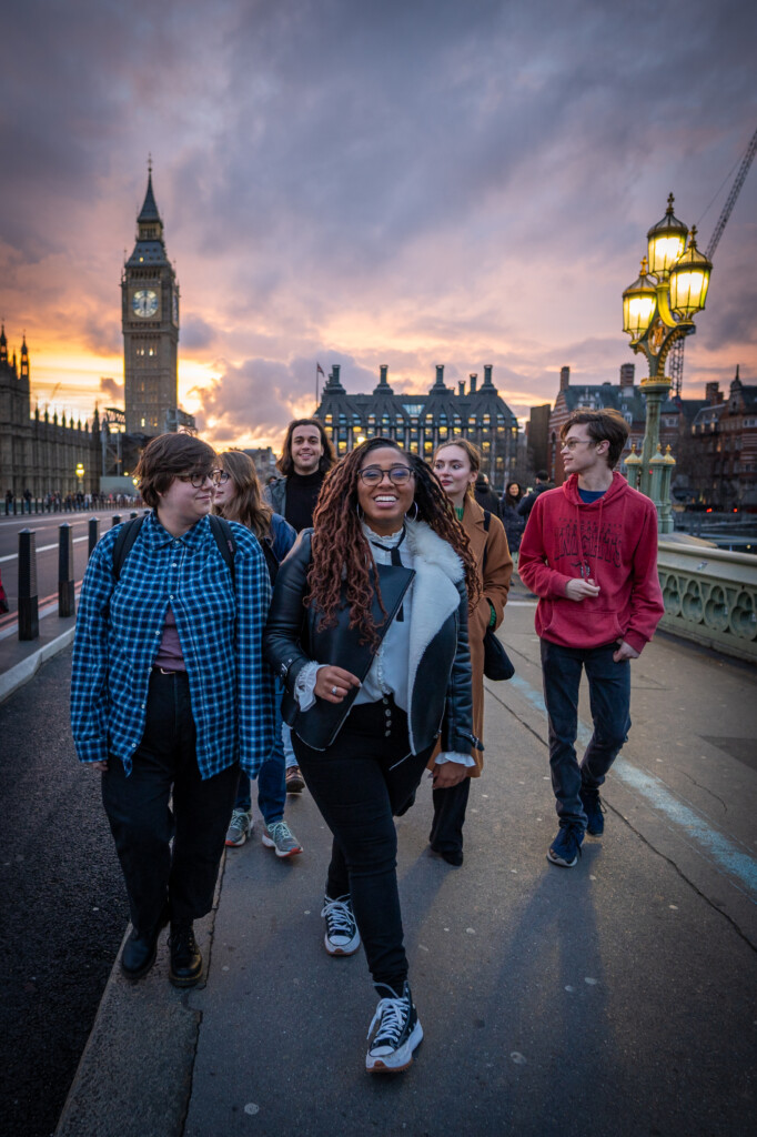 Students crossing a bridge in London at sunset.