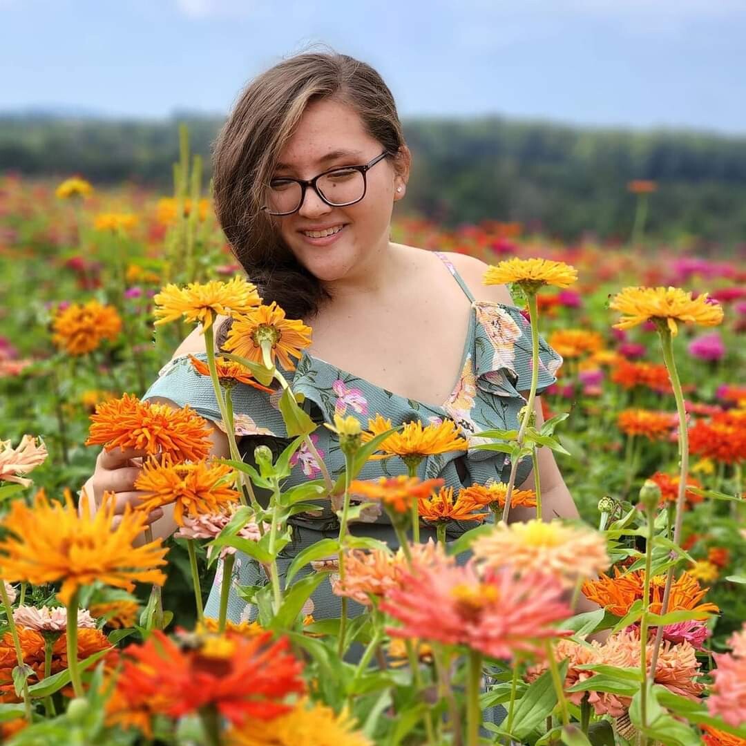 Grace Lamb '27 smiling in a field of flowers.