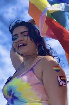 Courtney Thoroughgood waves a rainbow flag outdoors