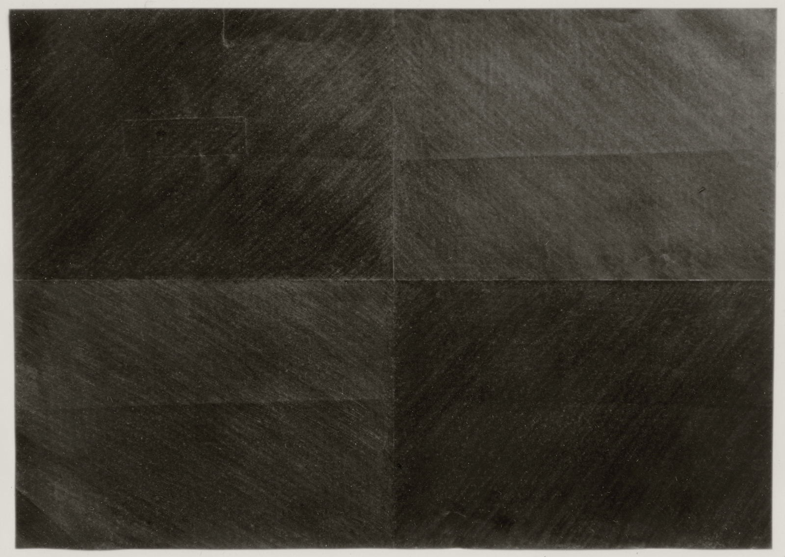 a folded piece of paper covered in graphite applied in directional hash marks