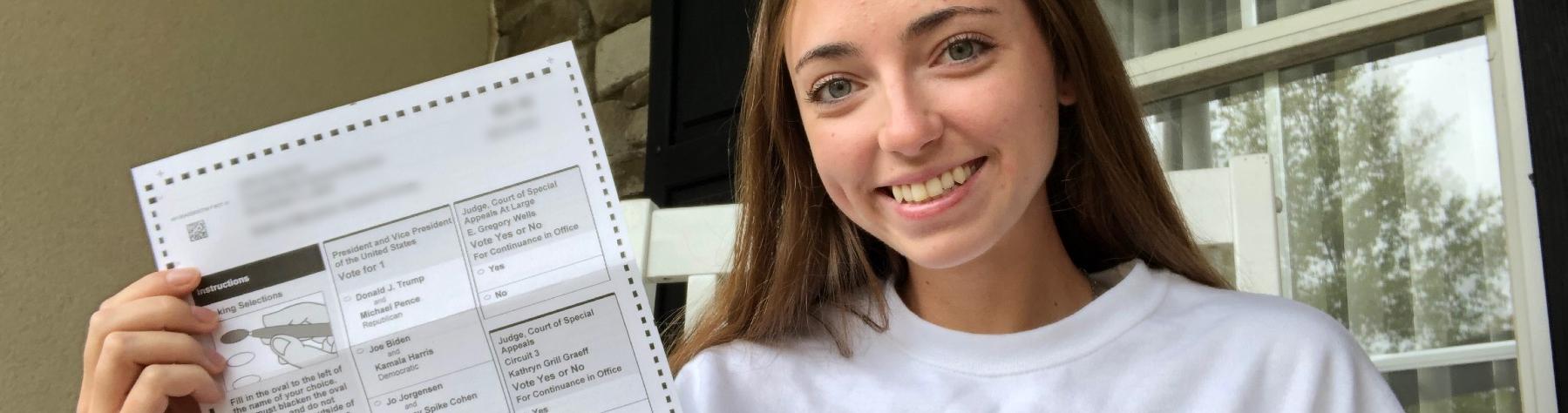 A student holding up a 2020 vote ballot.