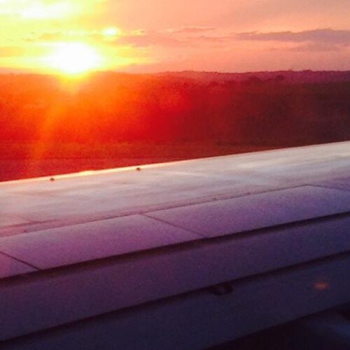 An airplane wing with a sunset in the background