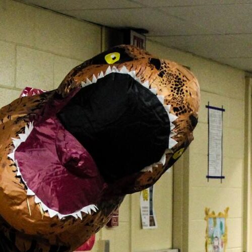 An inflatable t-rex head pops our from a resident hall room door