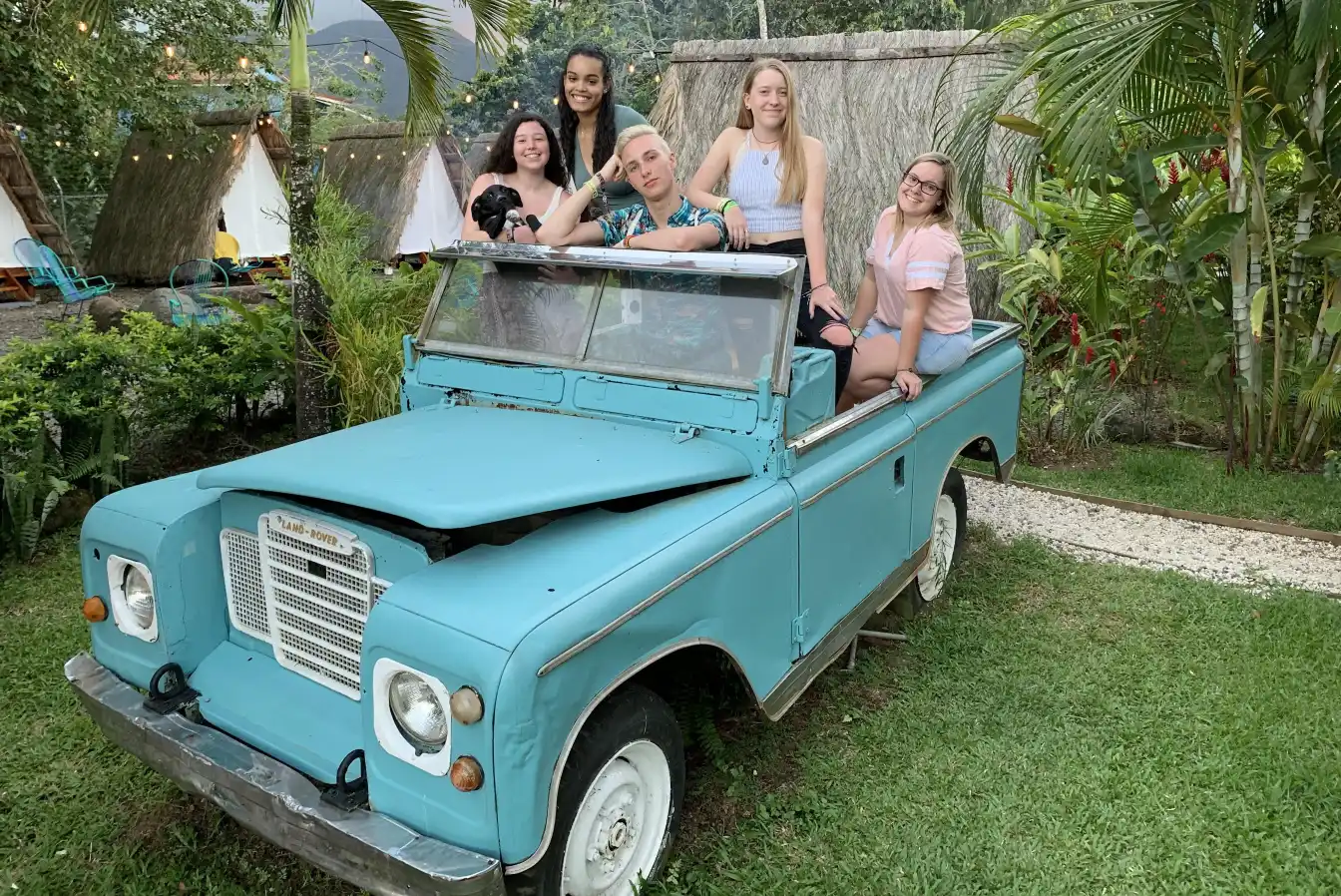 Students smiling and posing in a vintage baby blue truck while studying abroad in Costa Rica
