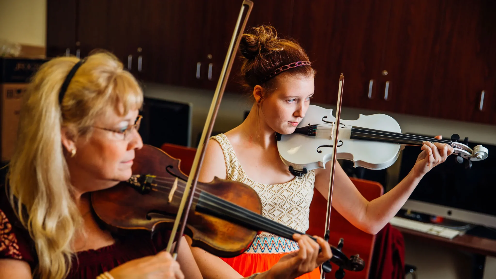 Student and professor standing and playing violins.