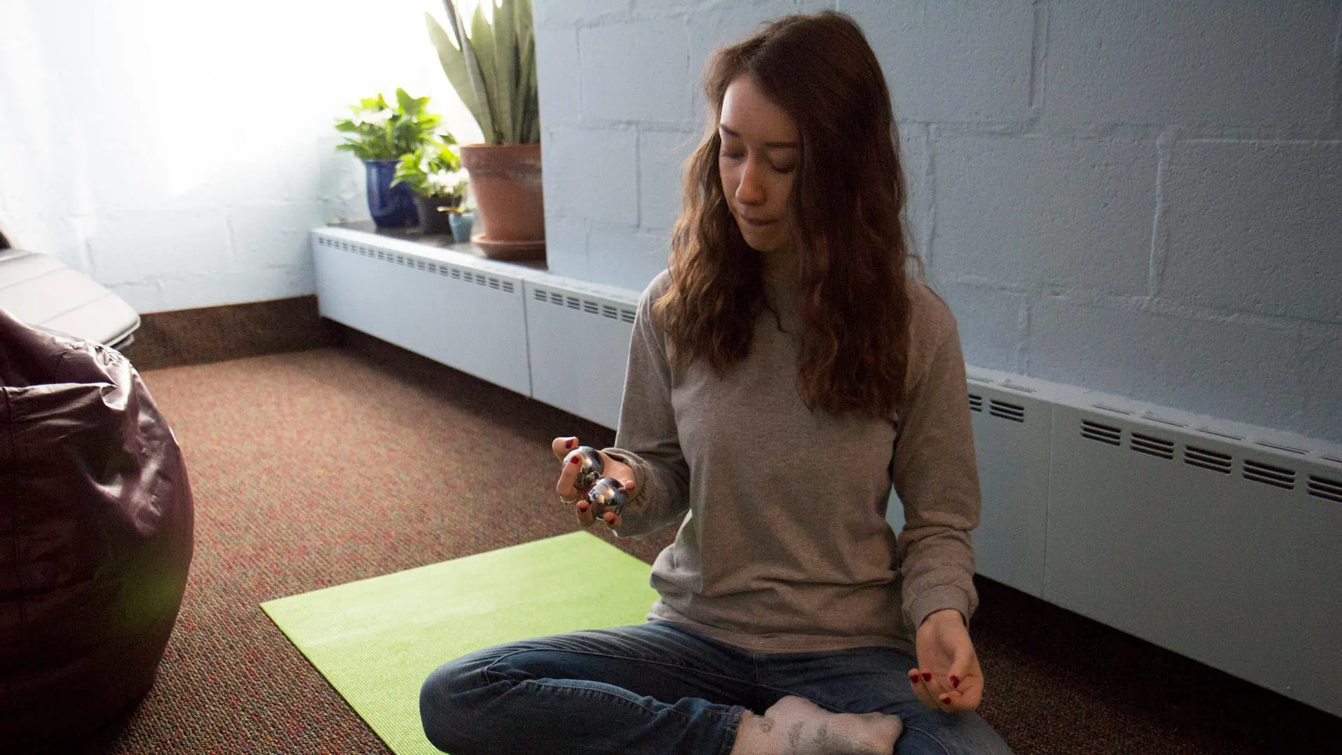 A student sits on a yoga mat in a meditative pose in the relaxation room