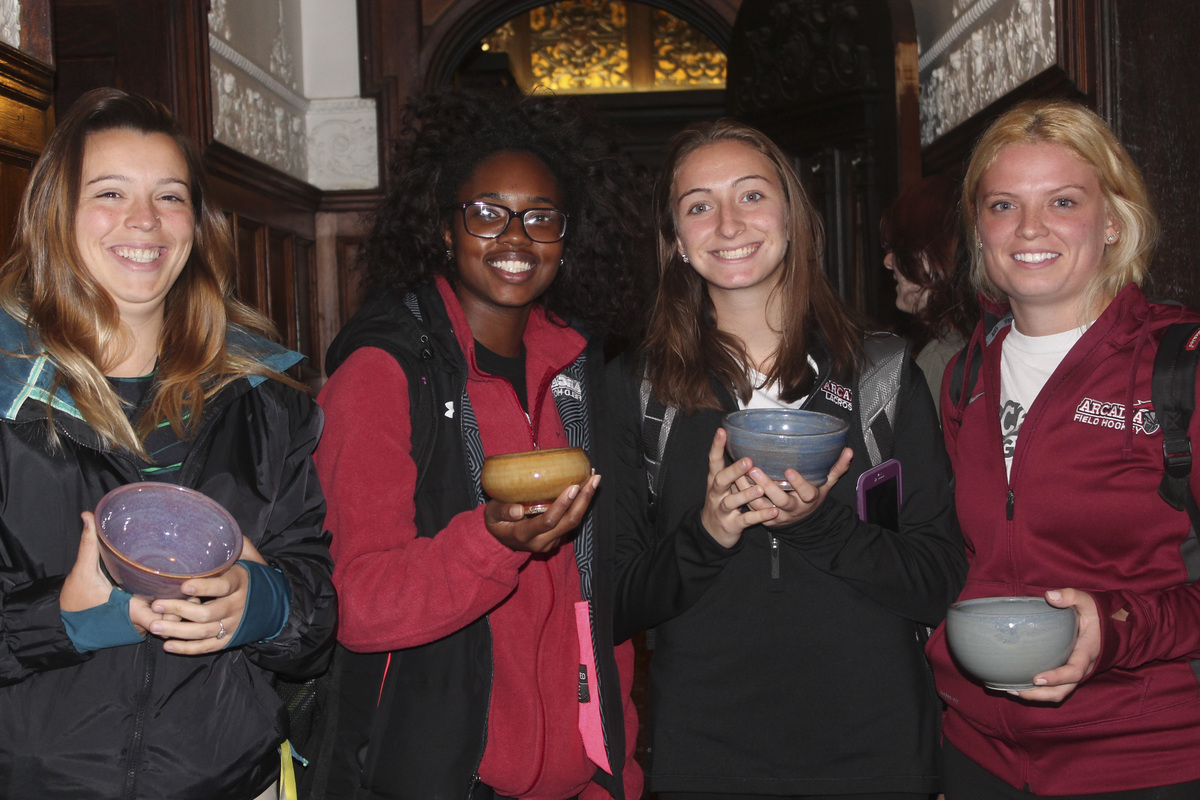 Four students show off their ceramic bowls during the Empty Bowl event.