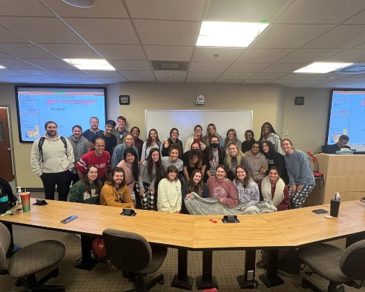 A large group of PA students gather at the front of their classroom.