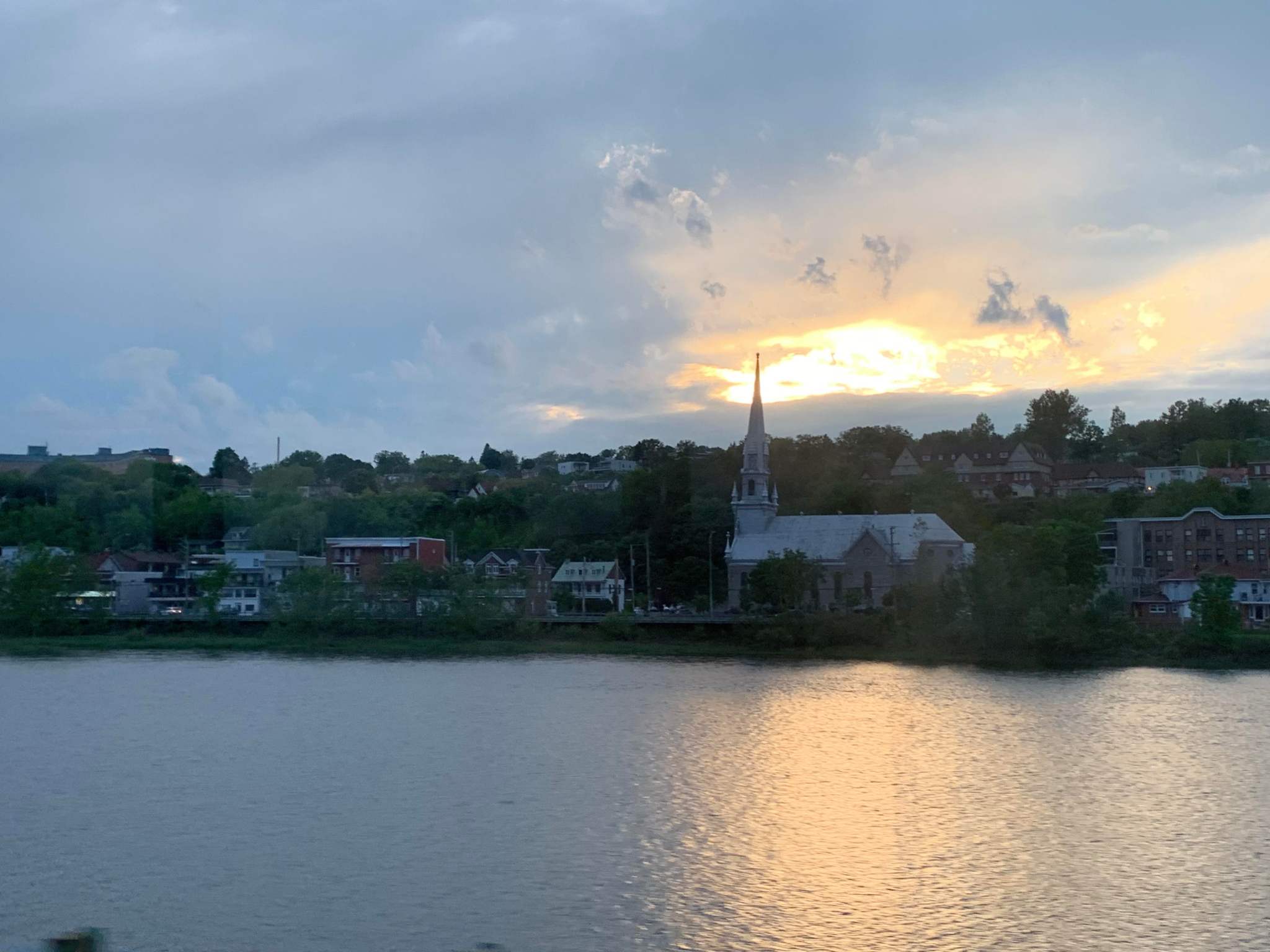 The sunset with a body of water in the foreground and a city in the background