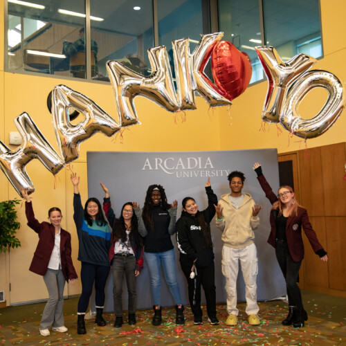 Students stand under balloons spelling out "Thank You"