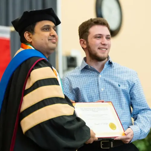 A student accepts an award from an Arcadia academic official at the Honors Convocation celebration.