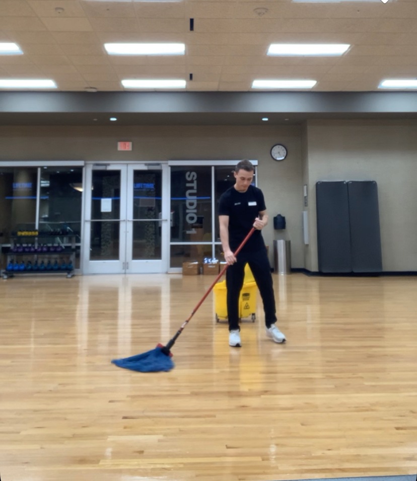 Patrick Ensmenger '23 mopping a wood floor