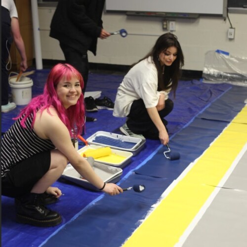 Students paint the Cheltenham mural at 125 Royal Ave using blue and yellow paint