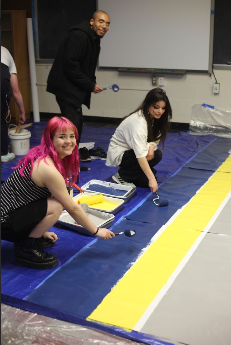 Students paint the Cheltenham mural at 125 Royal Ave using blue and yellow paint