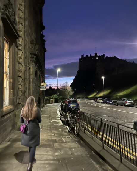 student walking at sunset down cobblestone streets of Ediburgh