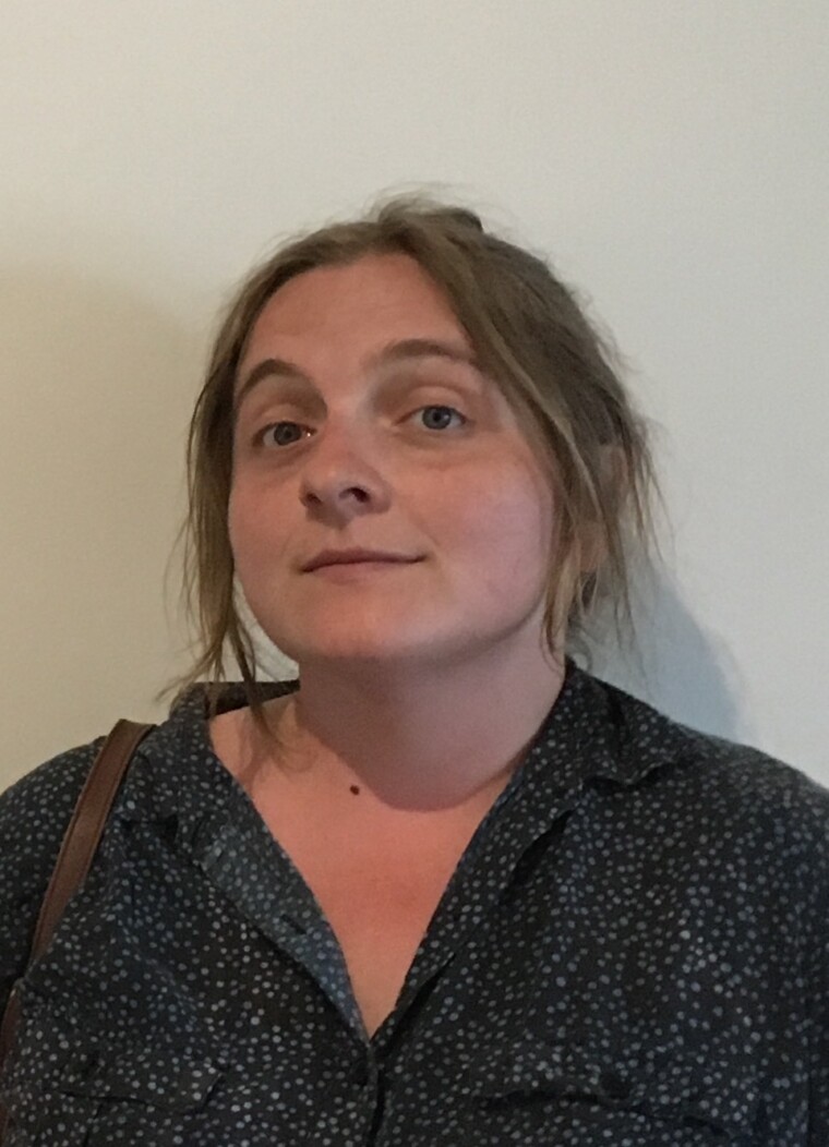 The headshot of a woman white-dotted black shirt.