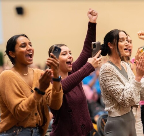 Students filming and celebrating in a conference.