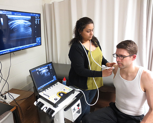 A physical therapist takes a reading on a patient during an exam.