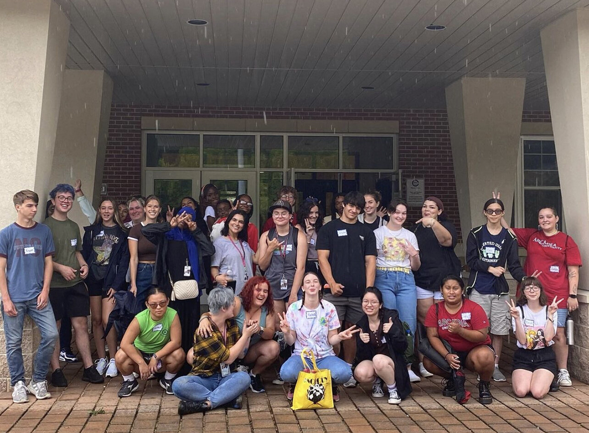 Community-based work-study students pose in a large group in front of a volunteer site.