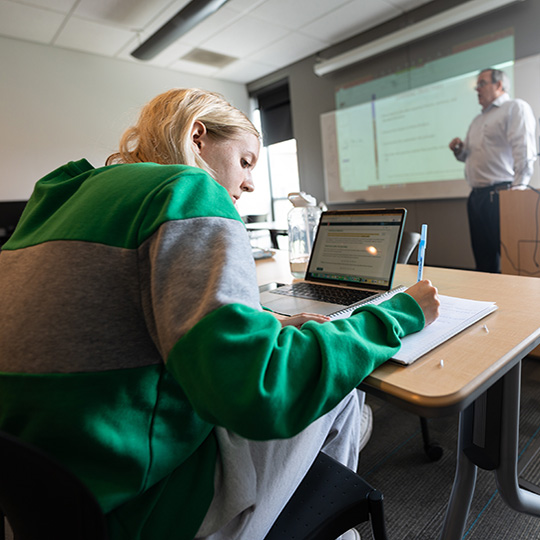 A student takes notes during class at the School of Global