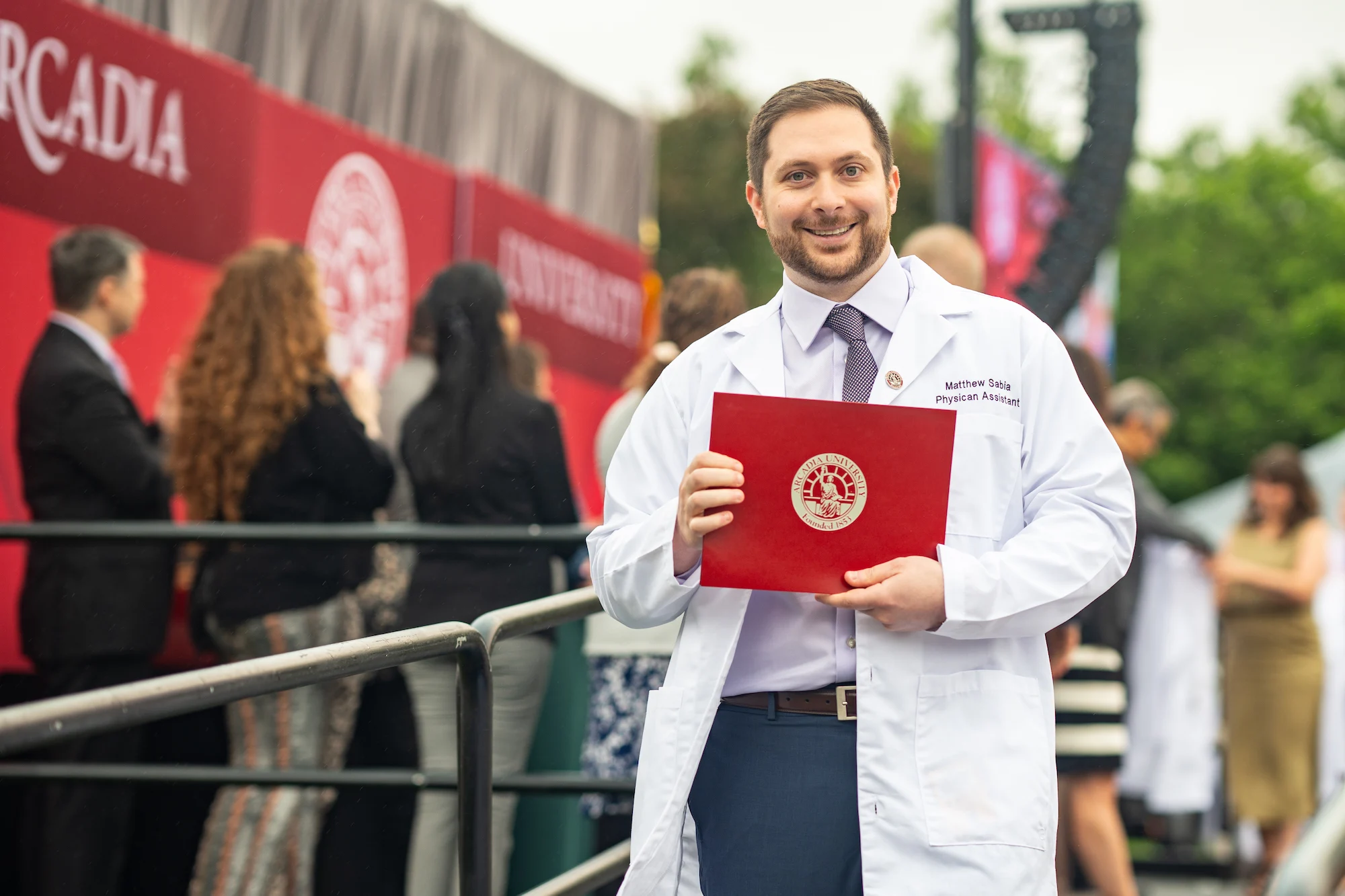 A student with their white coat and diploma.
