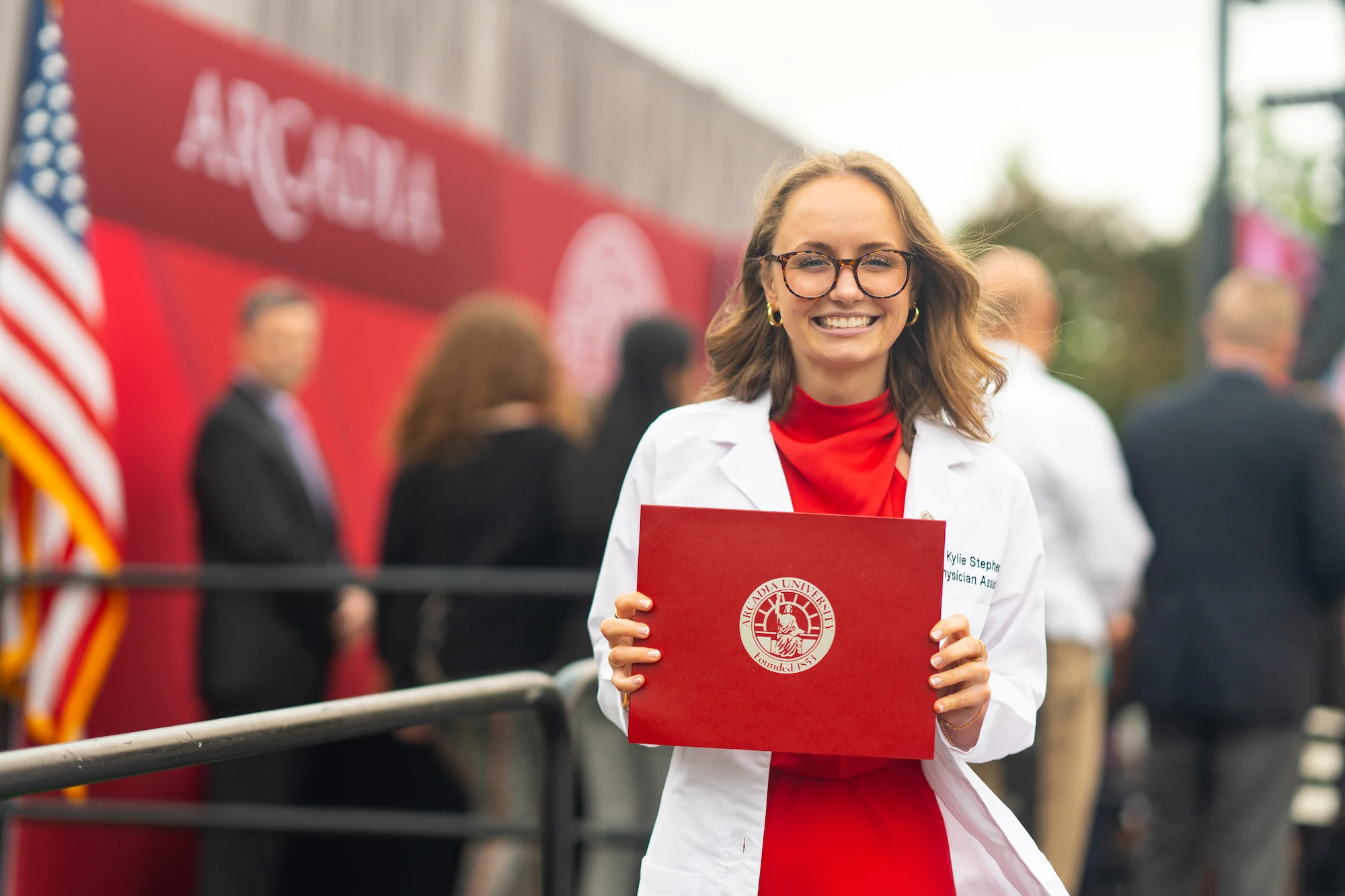A student with their white coat and diploma.