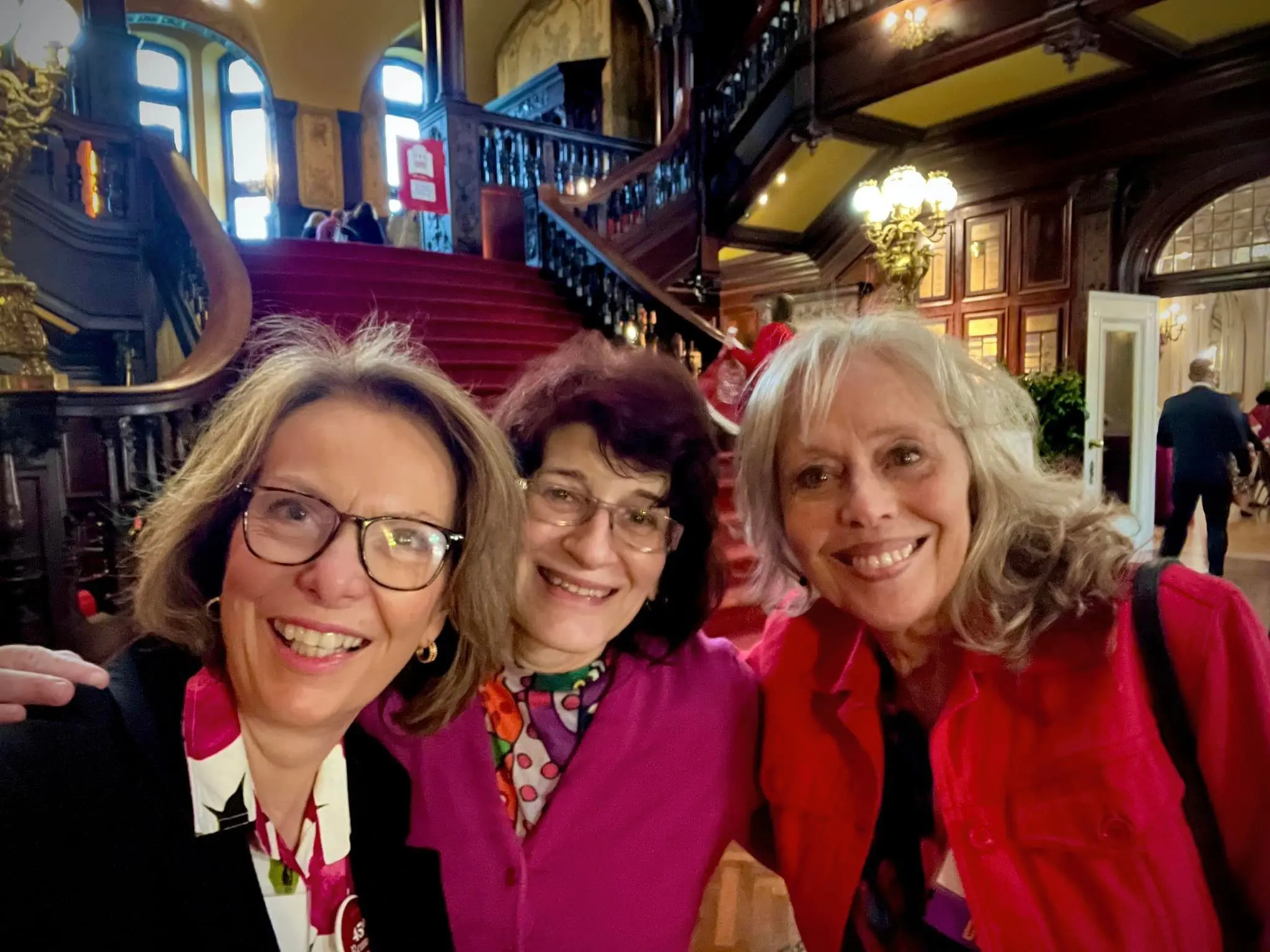 three alumnae standing together for a selfie picture in front of the stairs in the Grey Towers Castle