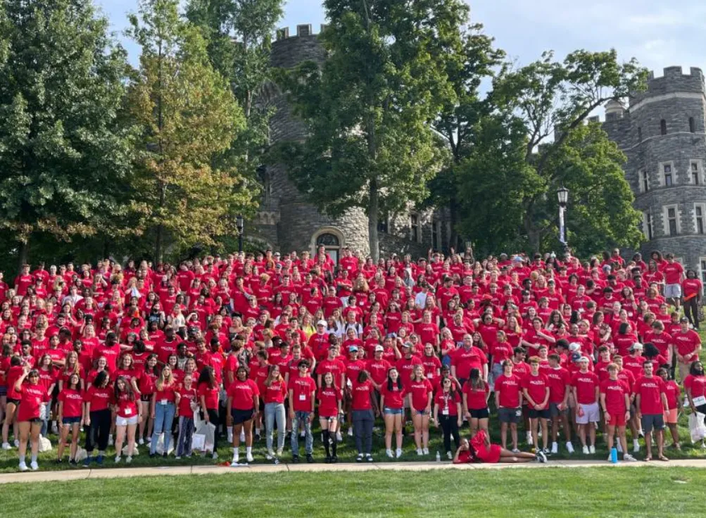 a large group of Arcadia students i red shirts stand in a group on campus