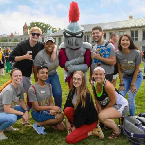 students pose with Archie the Knight, Arcadia's mascot, on Haber Green
