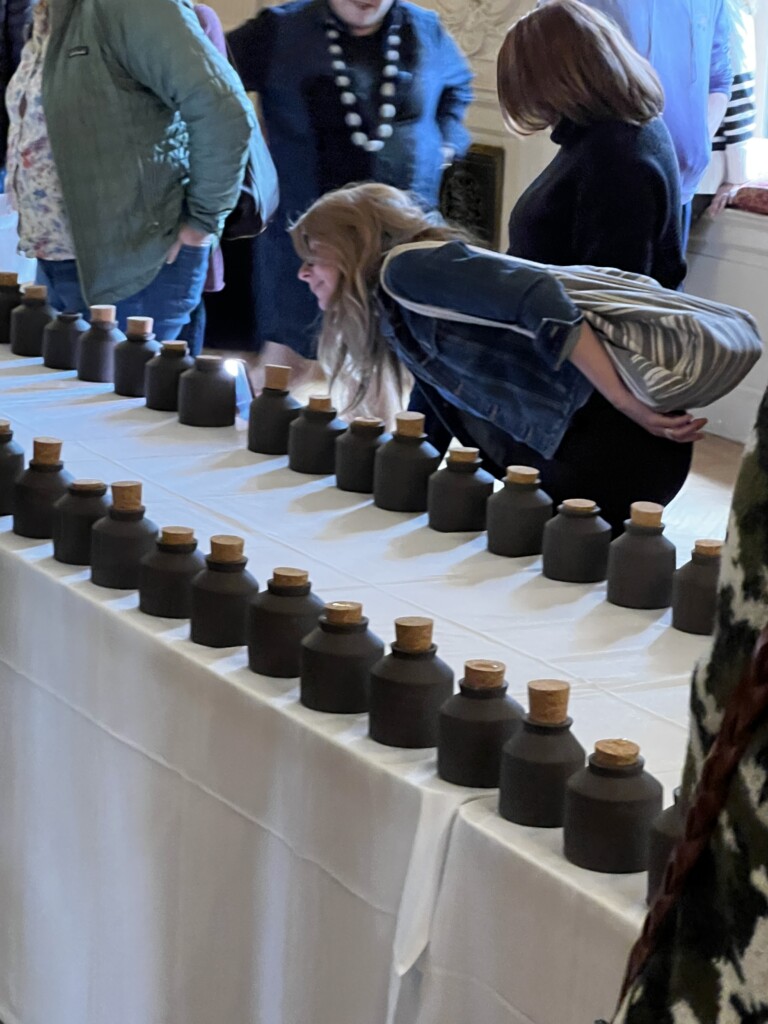 A table with black jar and people walking around