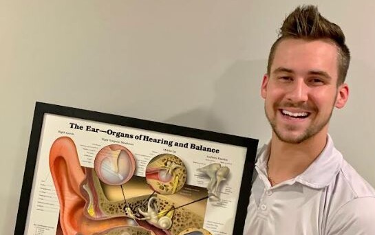 Kyle Kammerle holding a illustration of The Ear-Organs of Hearing and Balance